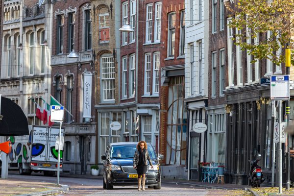 Uitvaartleidster loopt voor de rouwauto, afscheidsfotografie, Dordrecht binnenstad
