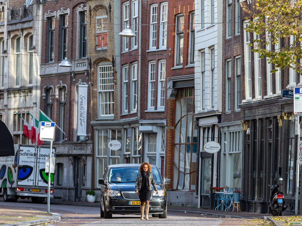 Uitvaartleidster loopt voor de rouwauto, afscheidsfotografie, Dordrecht binnenstad